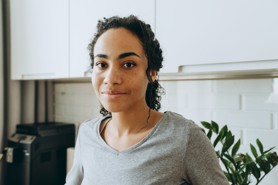 Young black woman smiling and looking at camera in kitchen